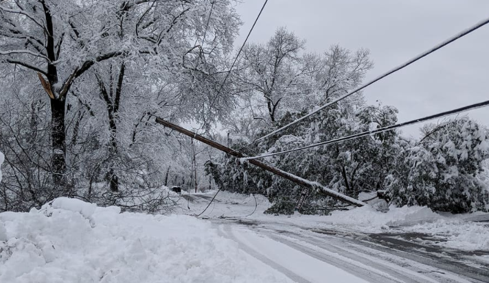 Downed power line blocking a road covered in heavy snow and ice.