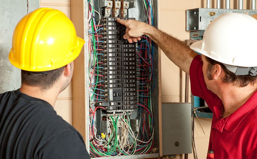 Two men in hard hats at an open electrical panel